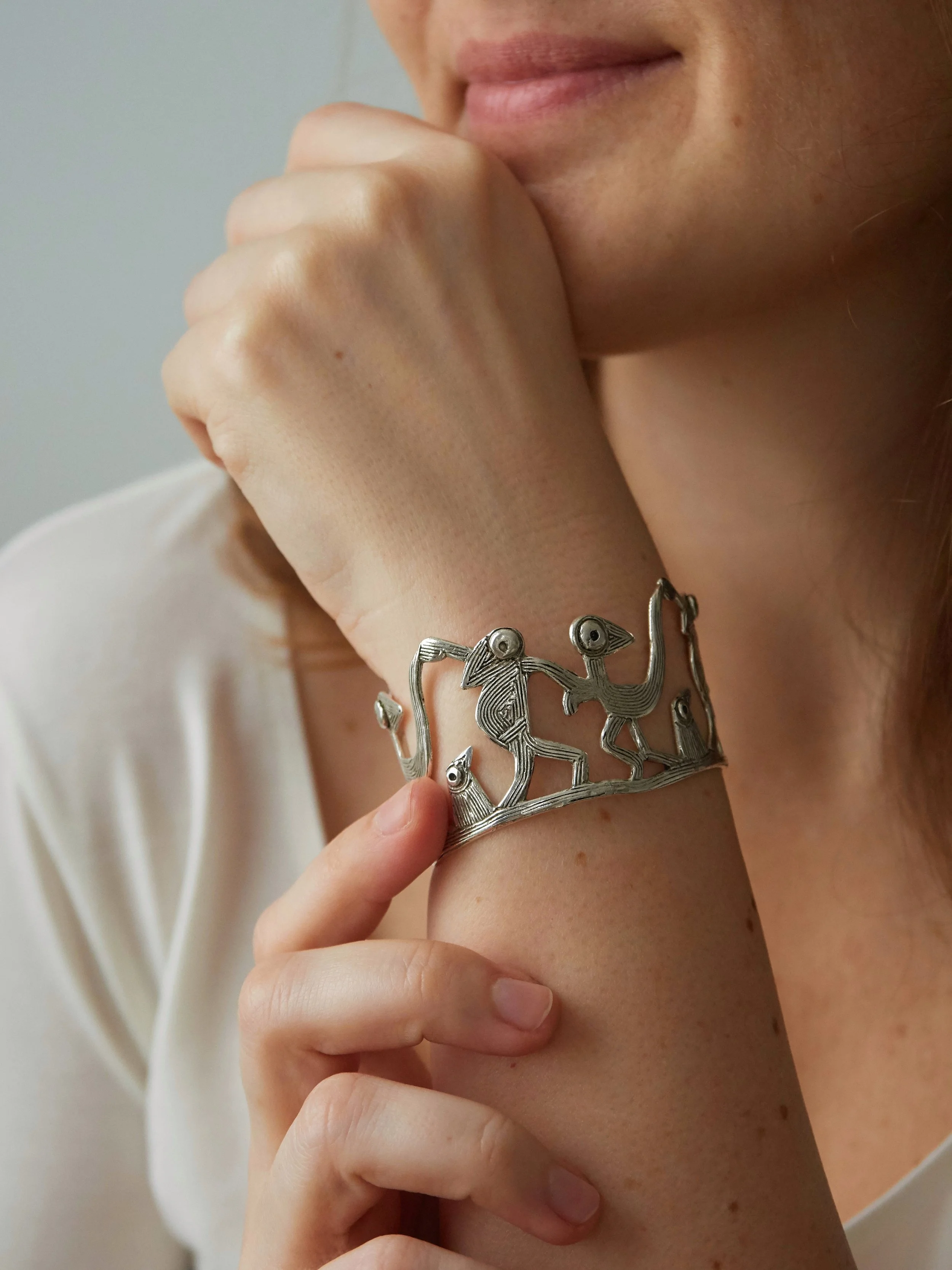 Detail of Farandole Dancing Birds bracelet in silver-plated bronze, handcrafted art jewellery with engraved spiral textures.