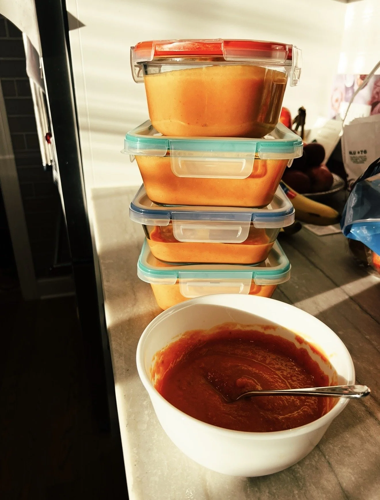 This image is of stacked storage containers filled with roasted butternut squash and vegetable soups for meal planning.