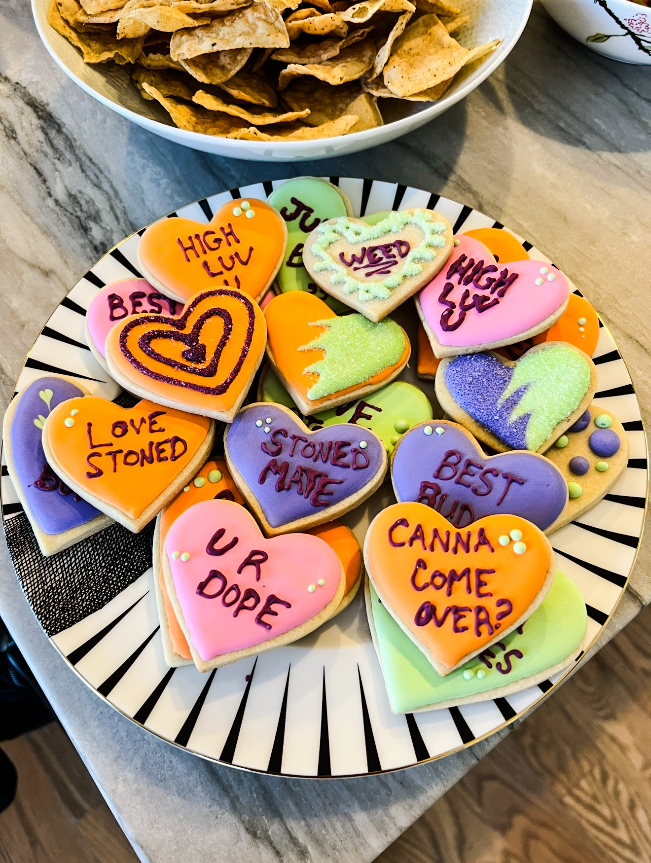 Photo of a plate of heart shaped cookies for weed smoking friends with cute saying on them like UR Dope, HIGH LUV, Best Bud, etc