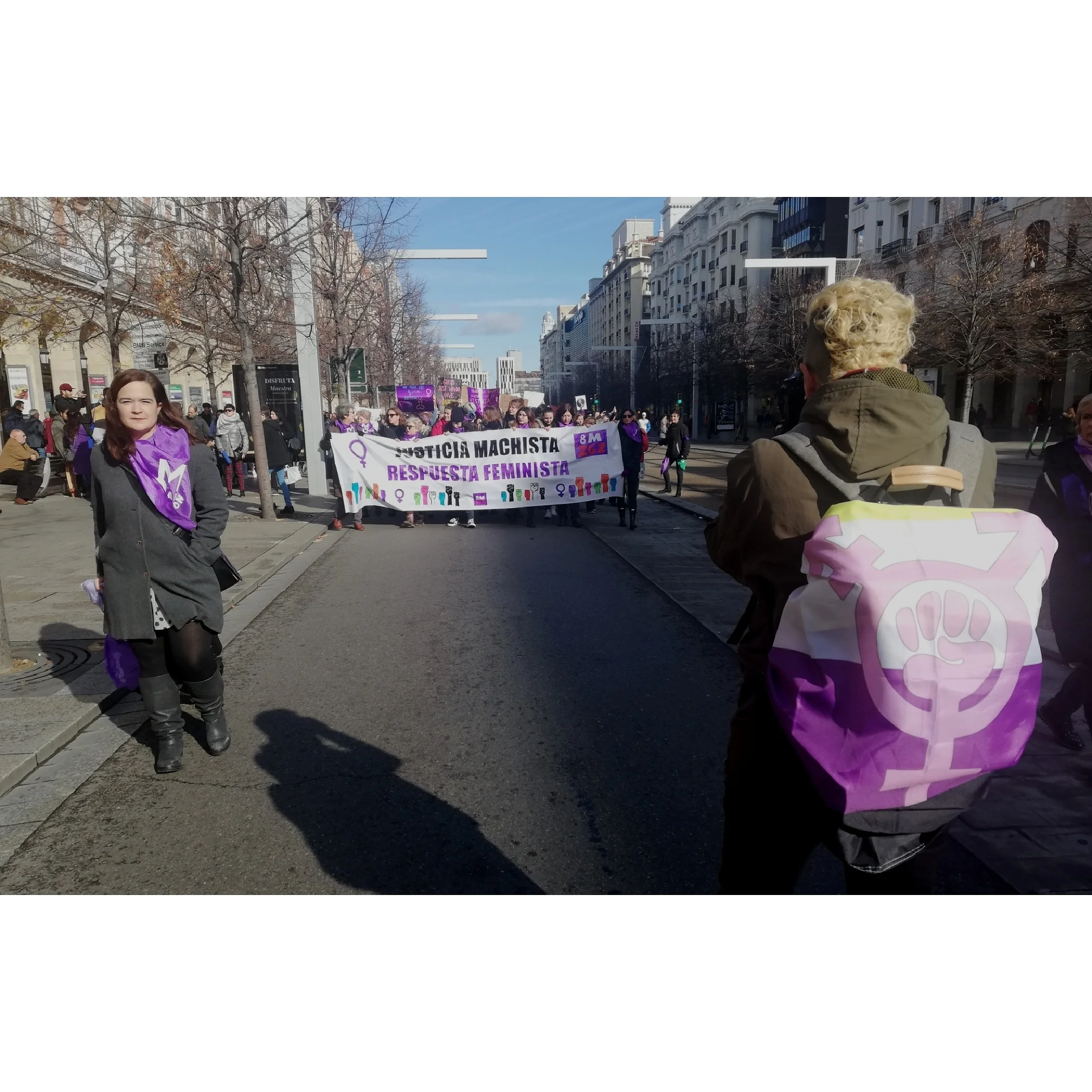 Dune Solanot fotografiando con la bandera no binaria y el símbolo transfeminista la manifestación del 25N, Día Contra la VIolencia Machista en Zaragoza.