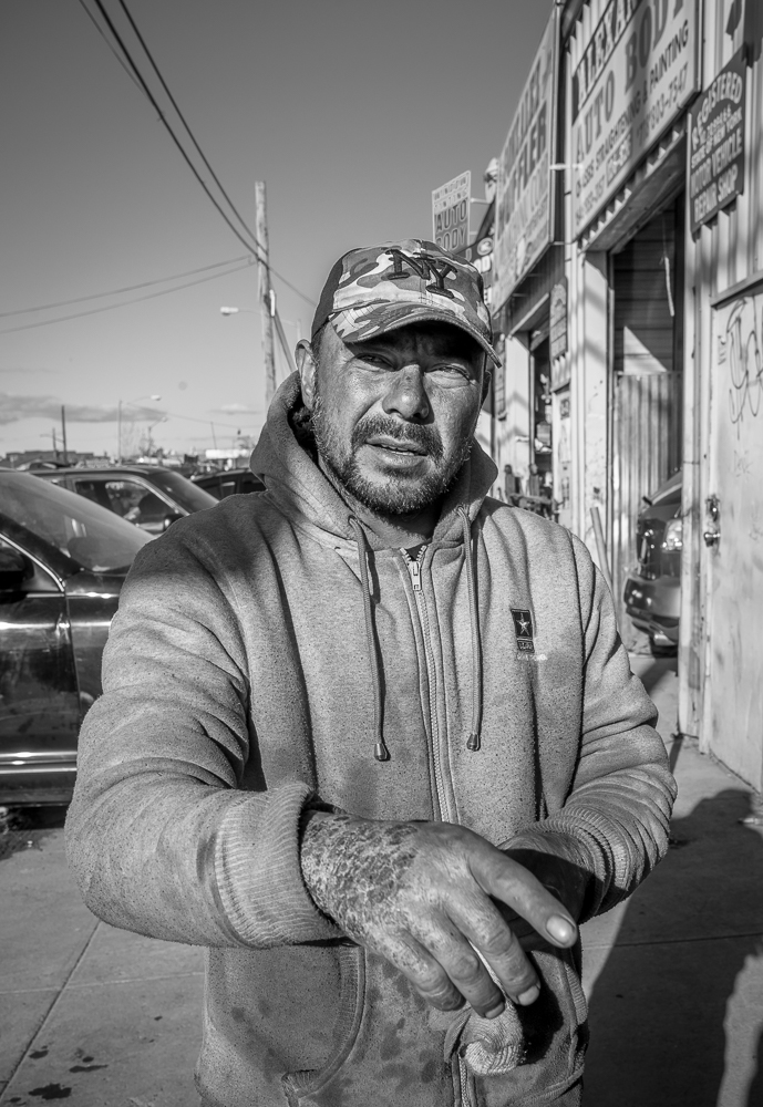 Oscar points to parts of Willets Point where some redevelopment has already taken place. His hand was badly burnt in a recent chemicals accident at the shop.