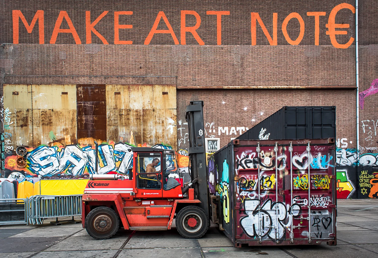 © Ayash Basu. Container boxes being moved to form a venue for a street art festival in a few hours. The shipping containers have many uses, including a canvas. "Make art not €," prominently displays on a massive wall of one of the warehouses.