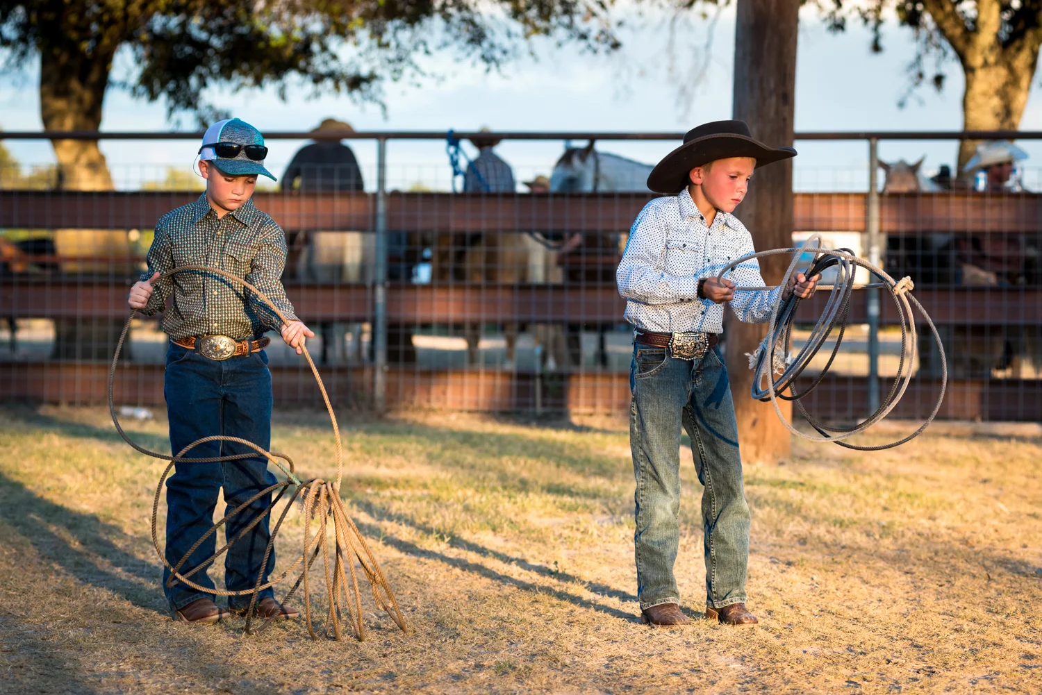 © Ayash Basu. Young boys often aspire to follow their father's footsteps and keenly refine their skills with the rope as grown up men compete in the adjacent arena. Bandera 2018.