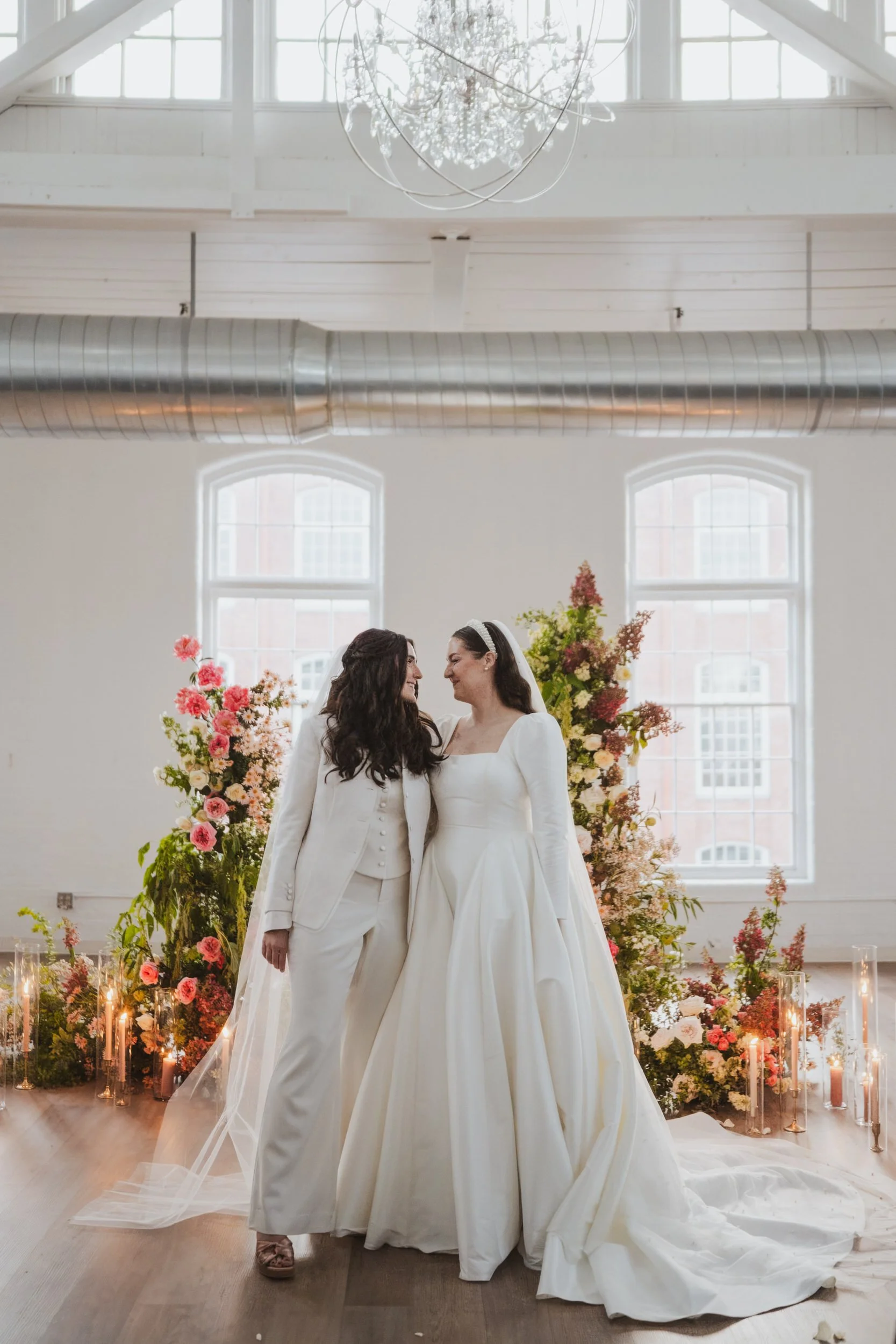 A newlywed couple standing side by side as they smile at each other