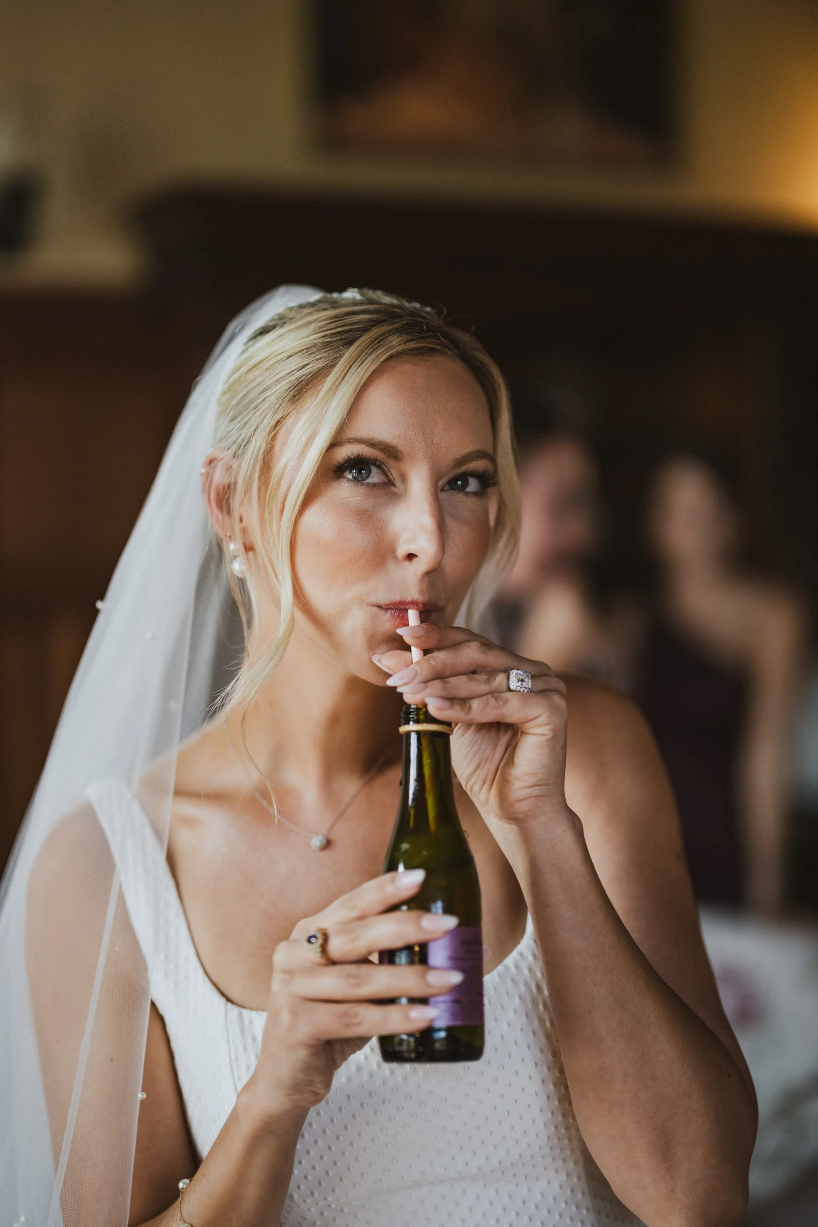 A newlywed in a wedding dress drinking out of a bottle