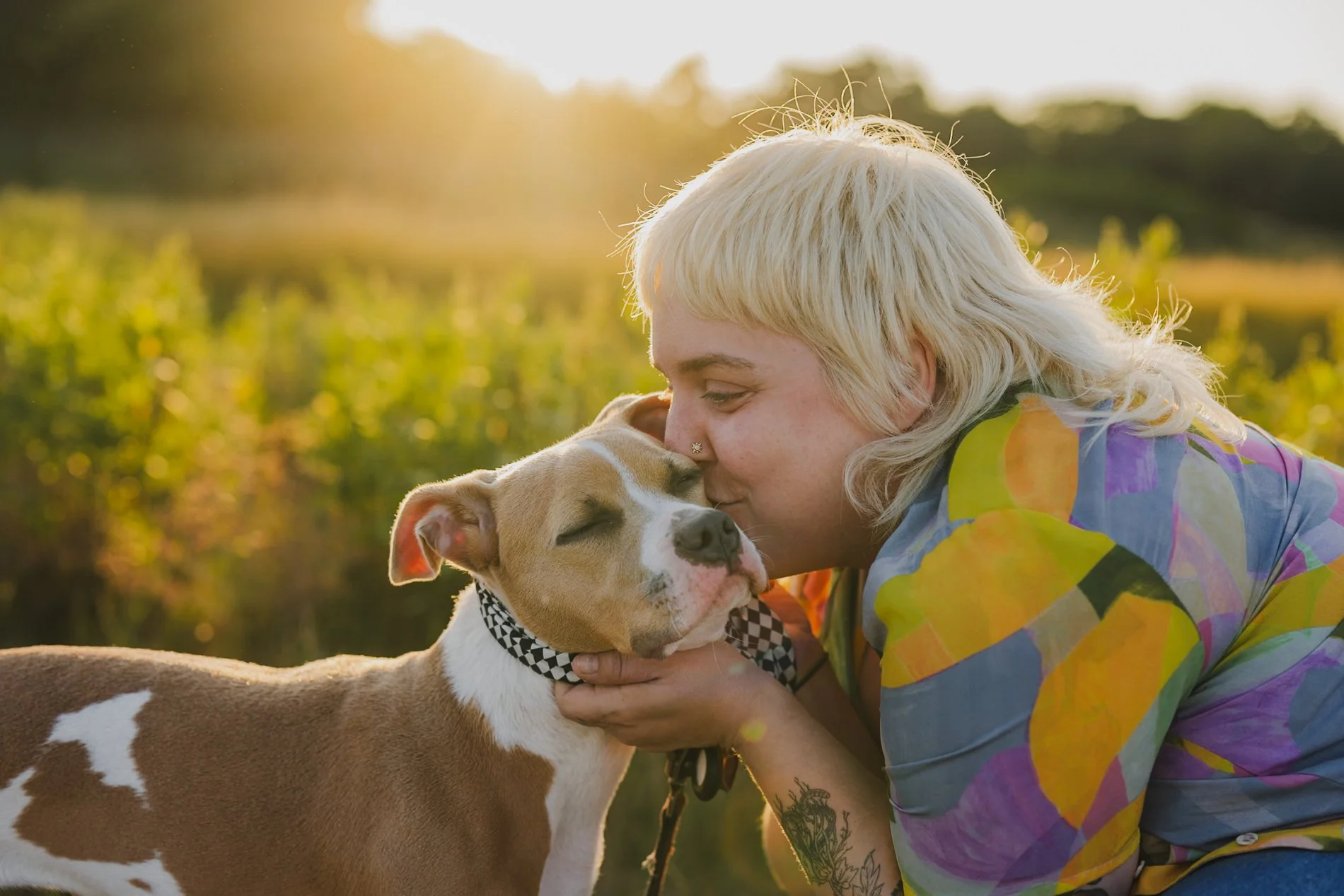 Amanda holding a dog's head as she kisses it