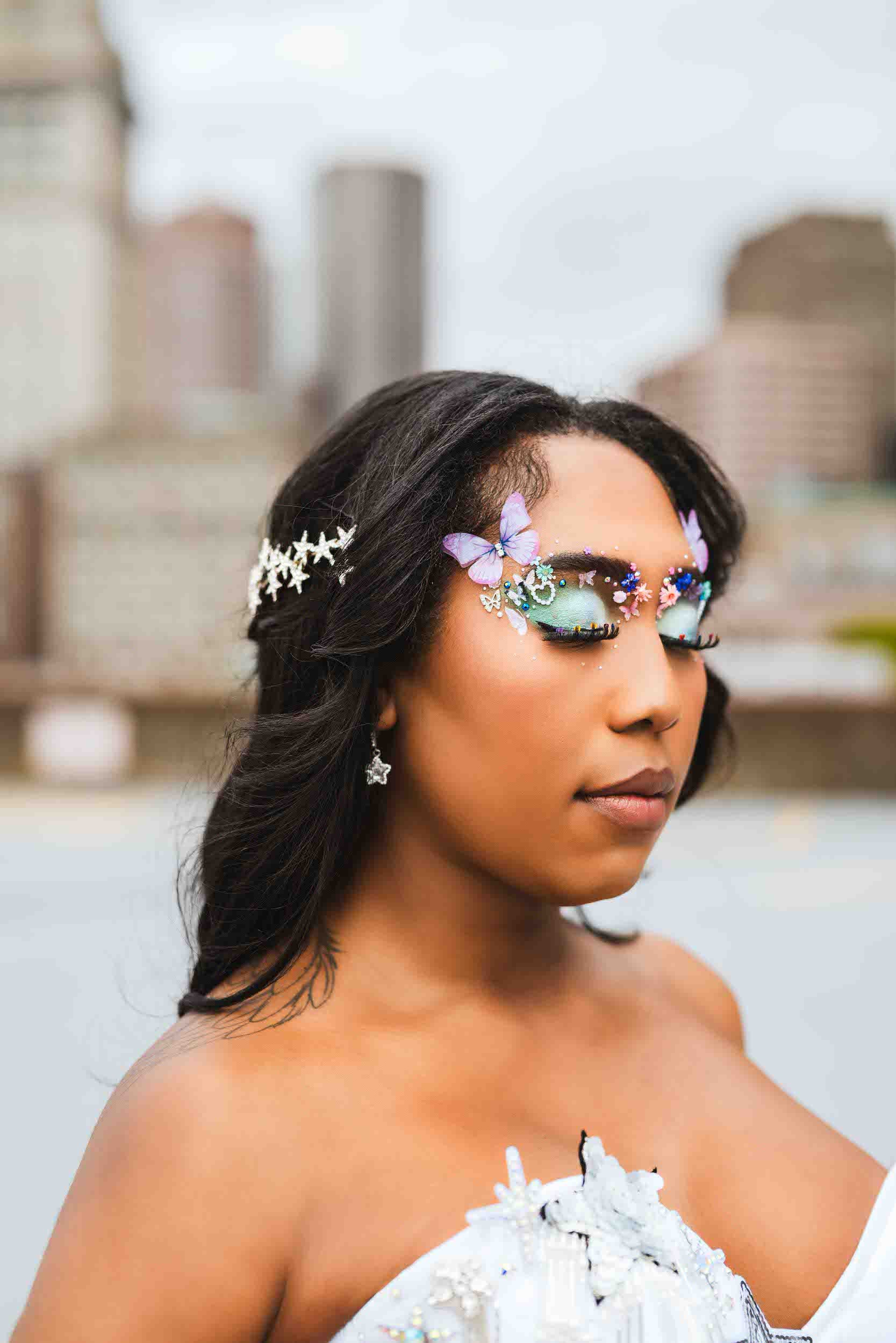 A person in a wedding dress with their eyes closed showing off elegant makeup