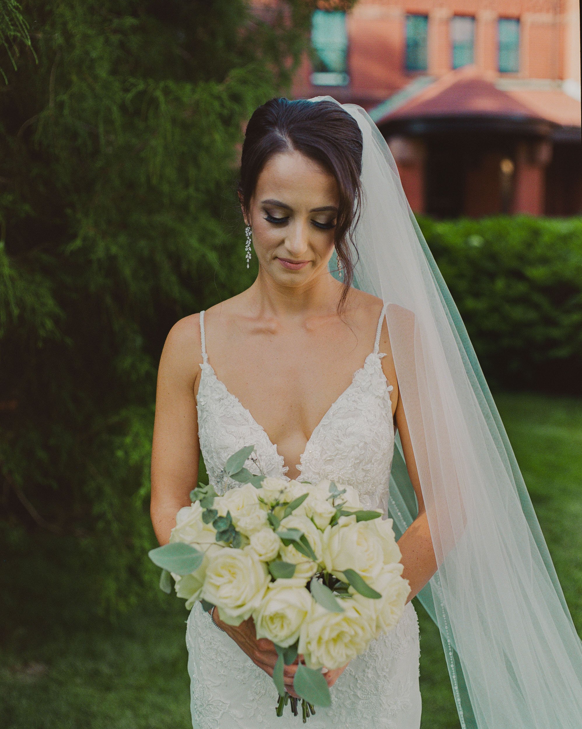 A newlywed in a wedding dress looking down at a bouquet of flowers in their hand
