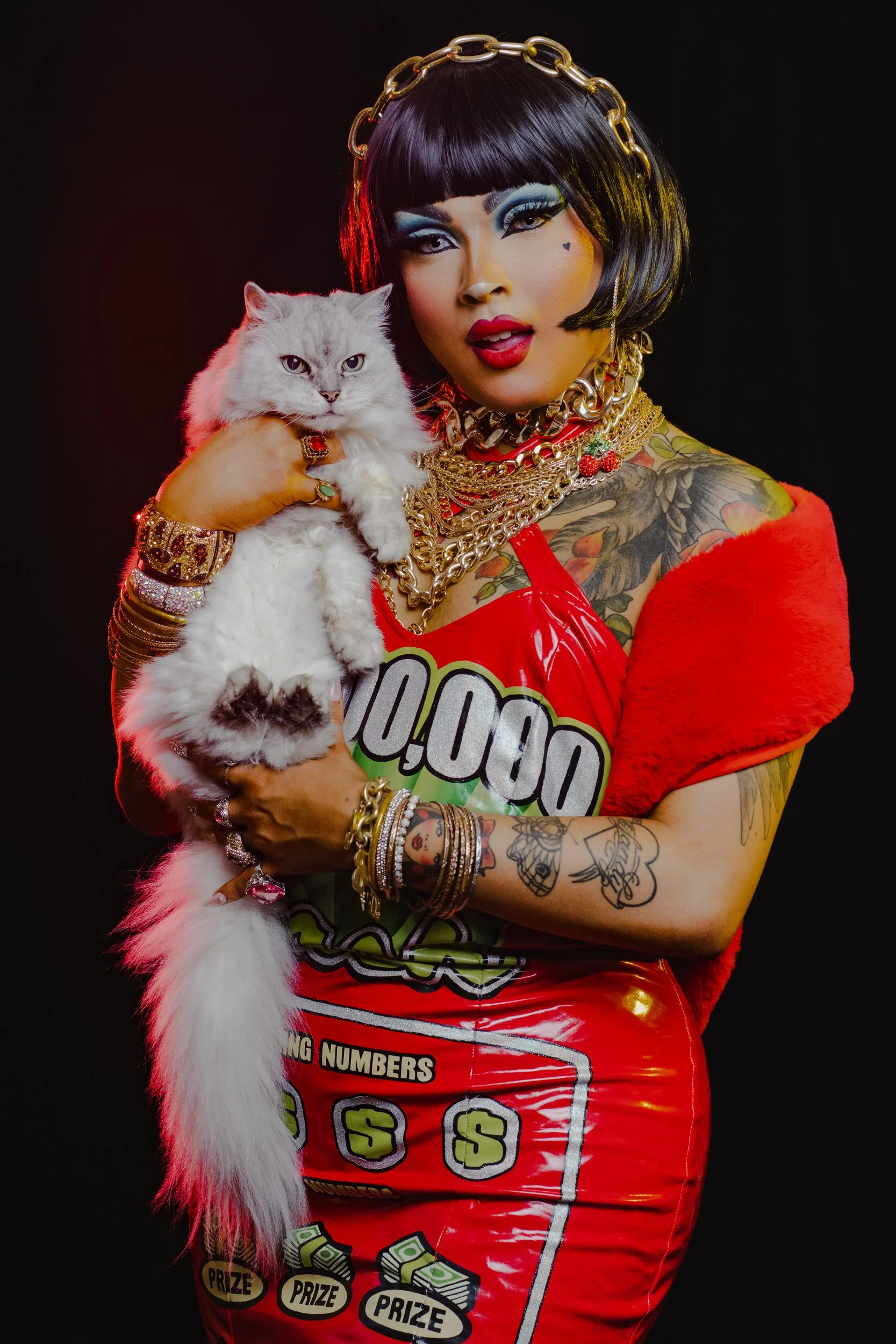 A person in full makeup posing while holding a cat