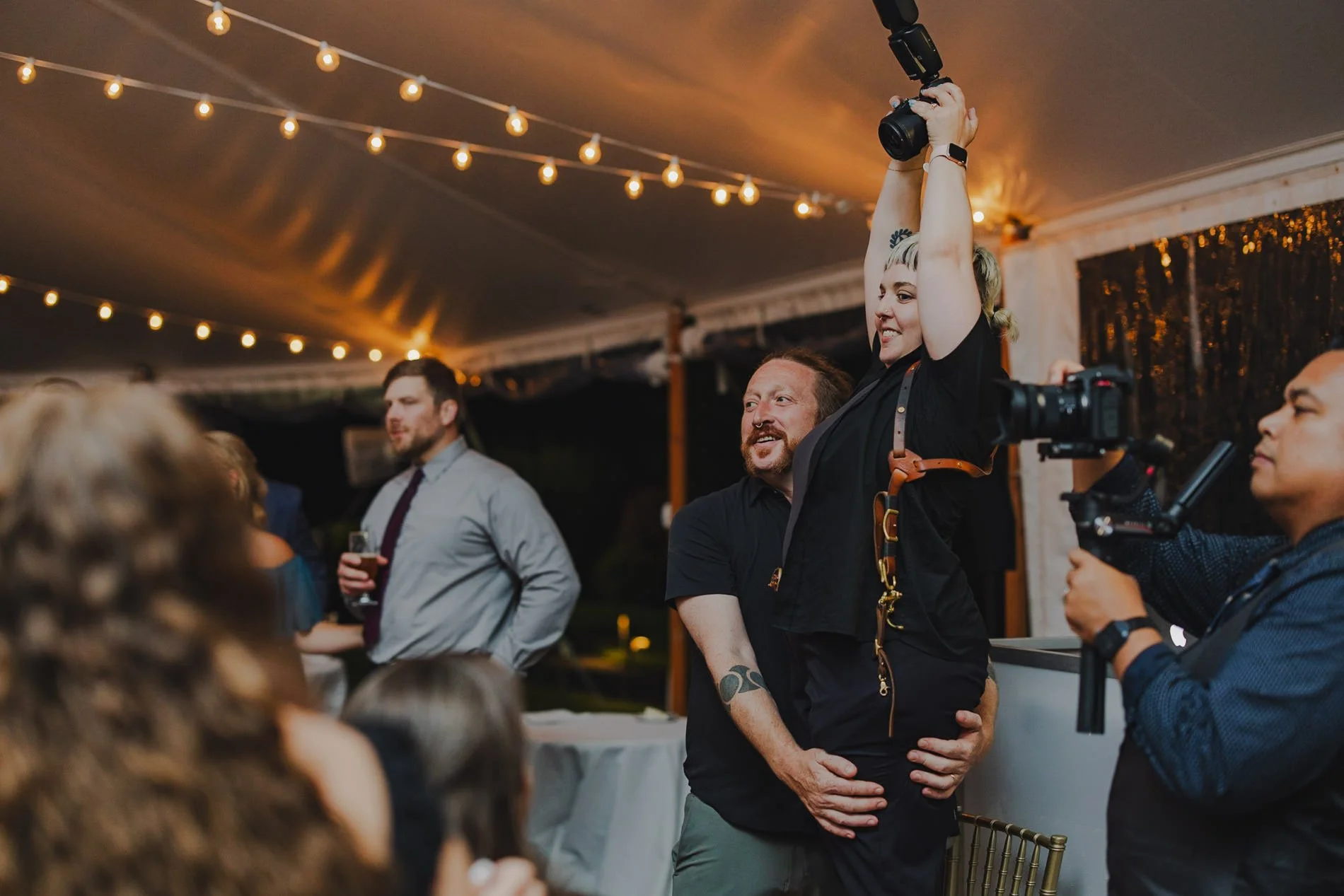 Mike holding Amanda up as she photographs a wedding reception