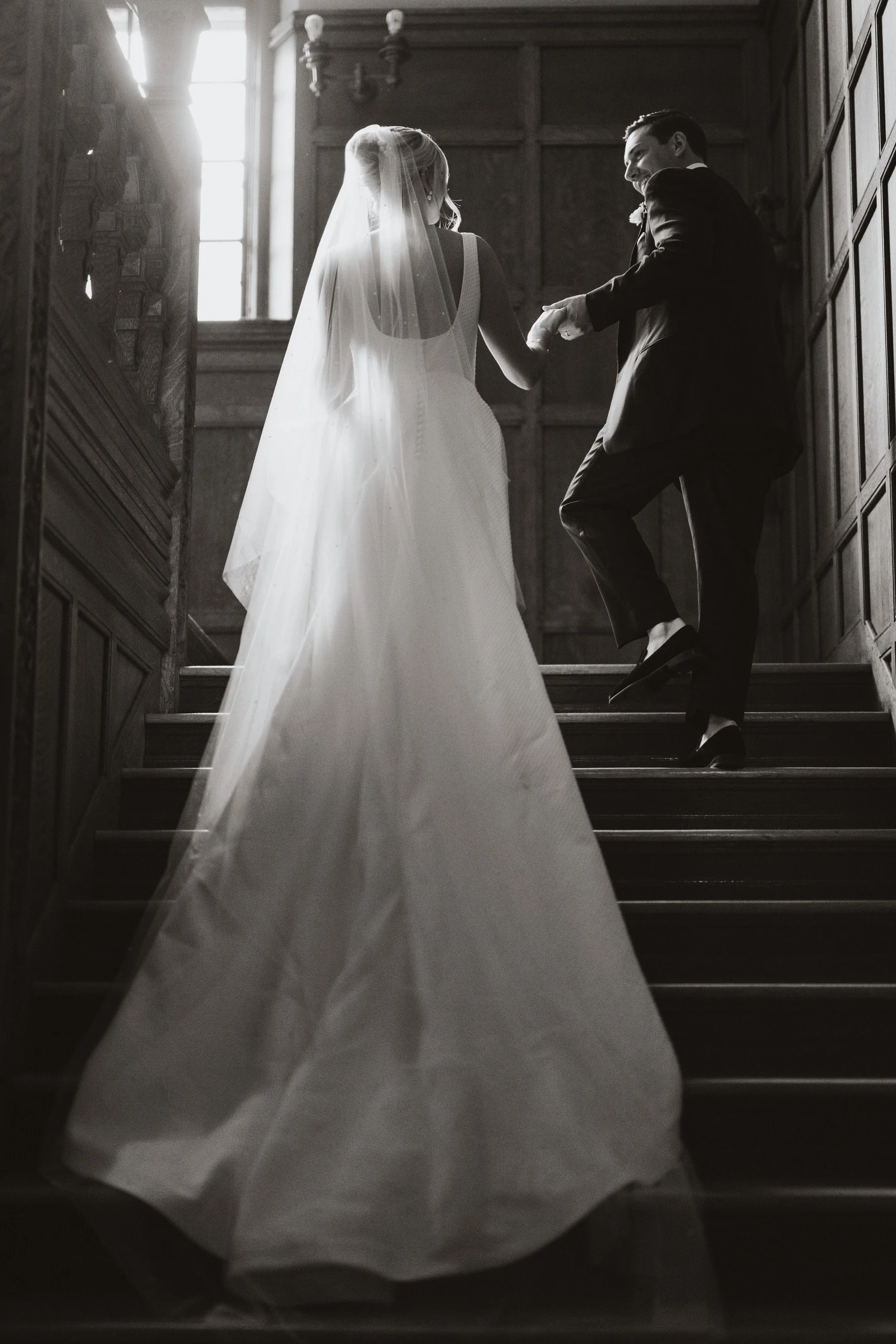 A newlywed couple holding hands and walking up a staircase