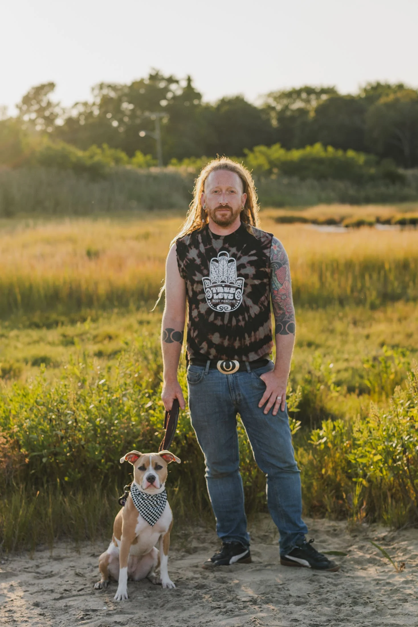 Mike standing in a field with a dog sitting next to him