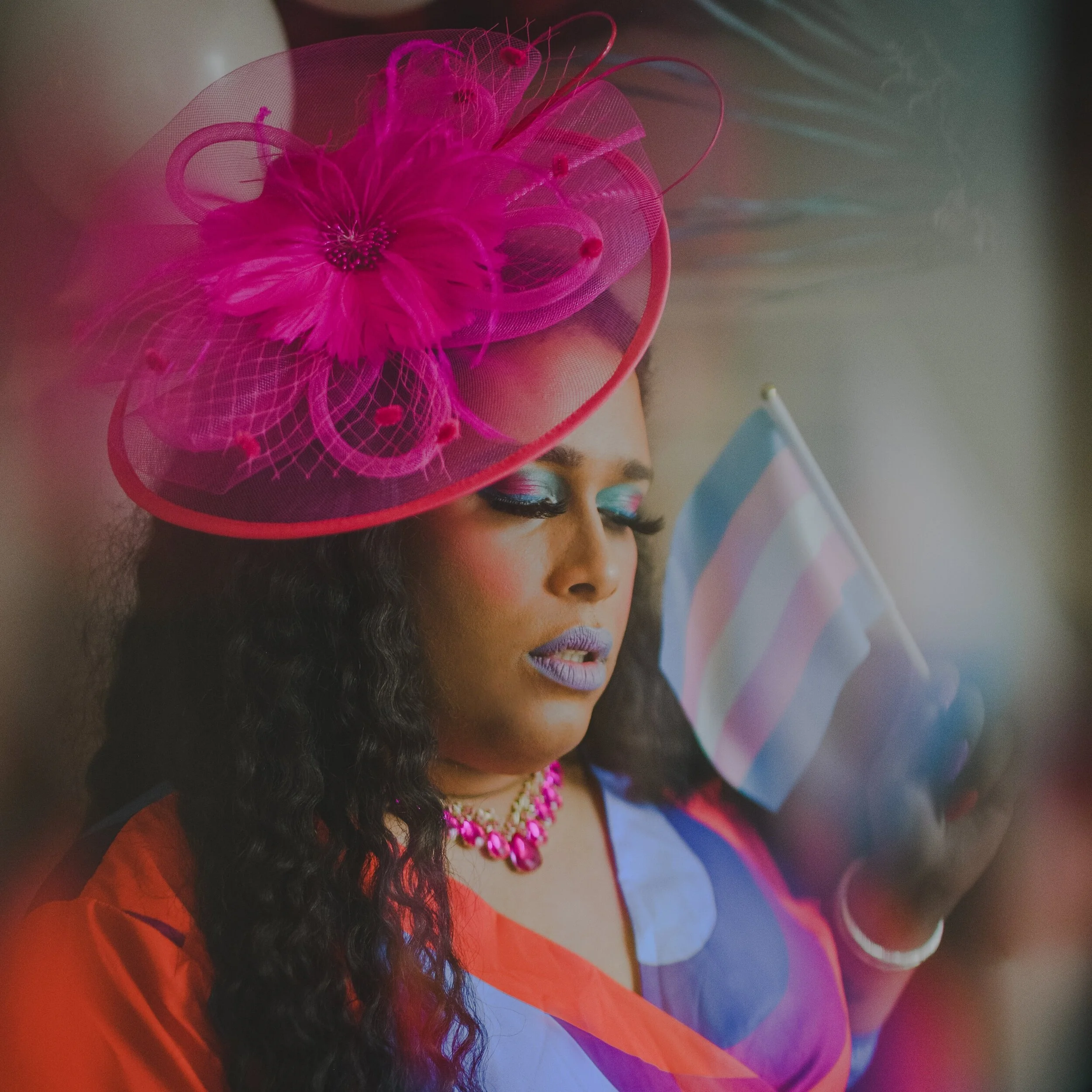 Trans activist and model poses with a pink hat holding the trans flag