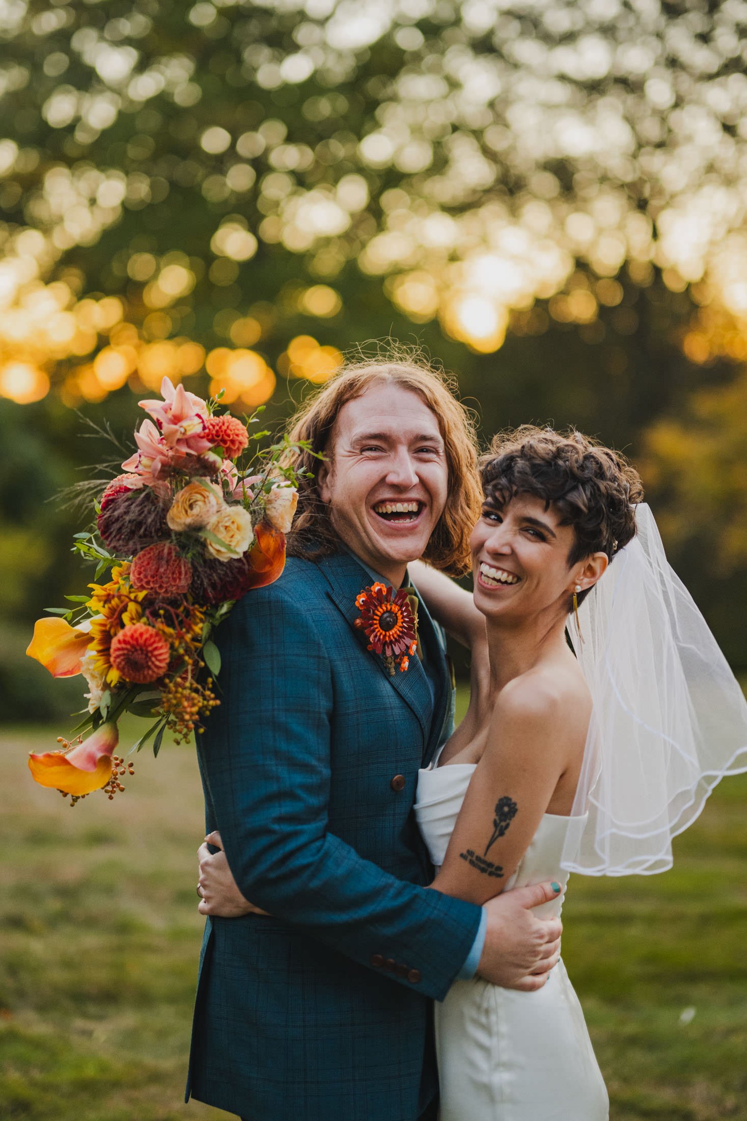 A newlywed couple with their arms around each other as they smile big