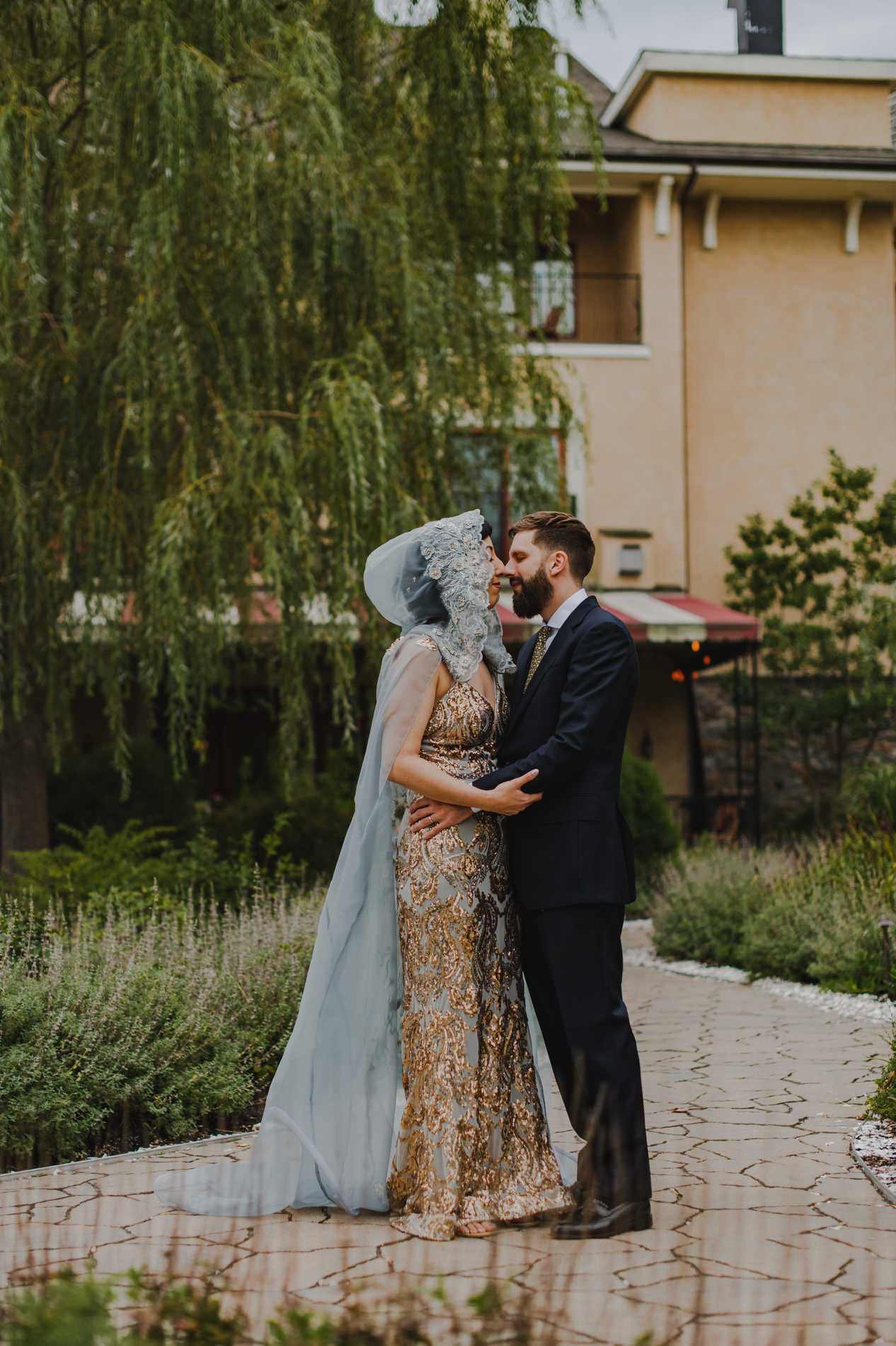 A newlywed couple leaning in to kiss in a small garden area