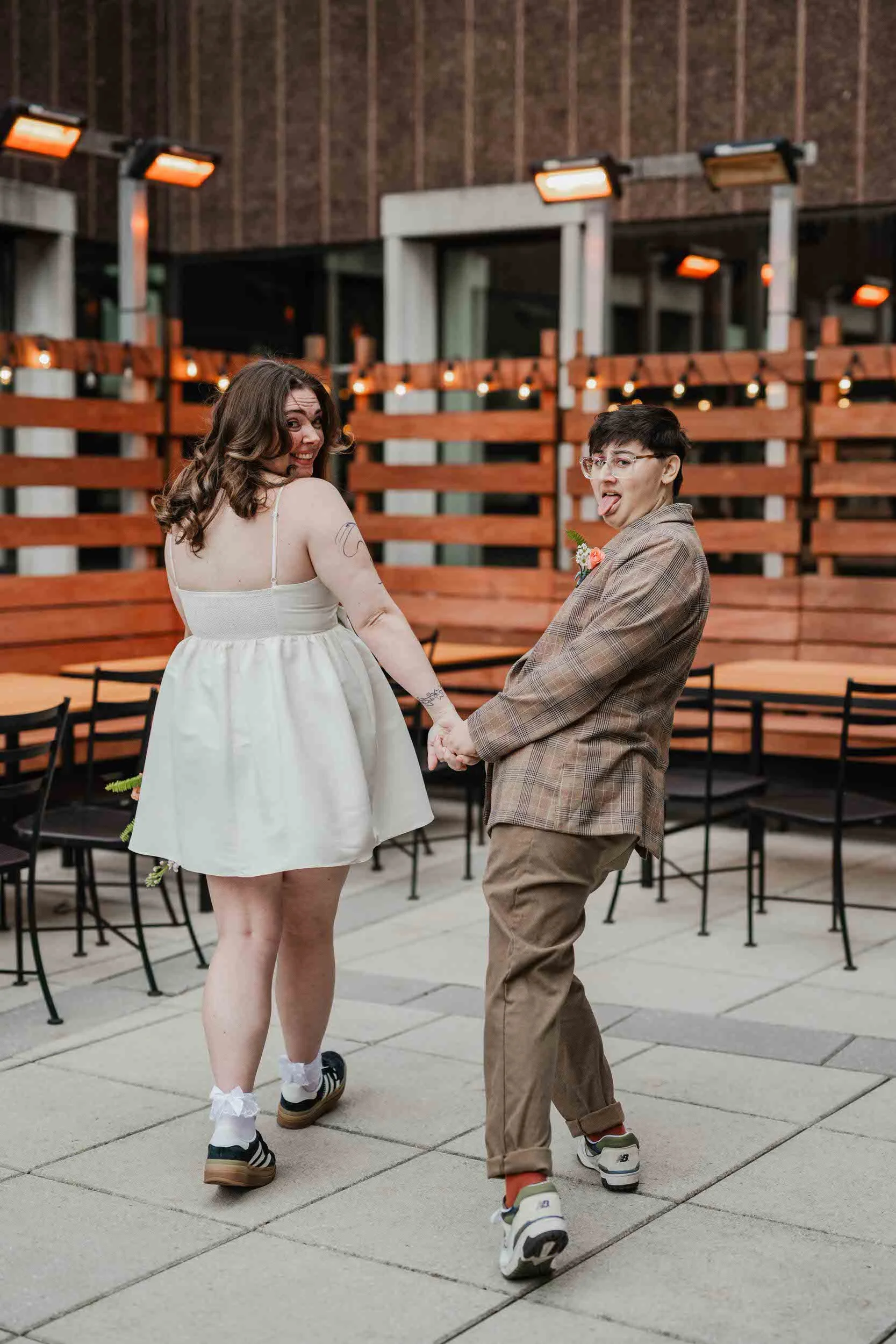 Newlyweds holding hands and looking over their shoulders as they make faces