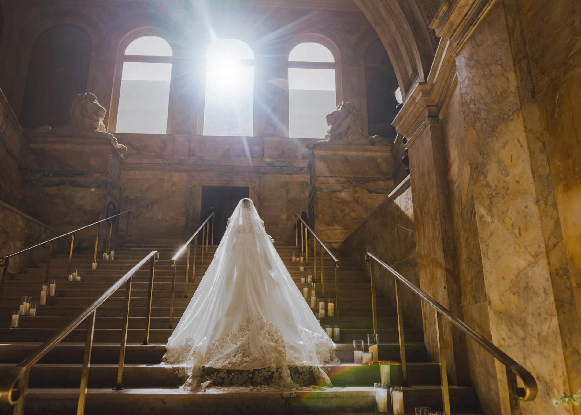 A newlywed in a wedding dress walking up a grand staircase