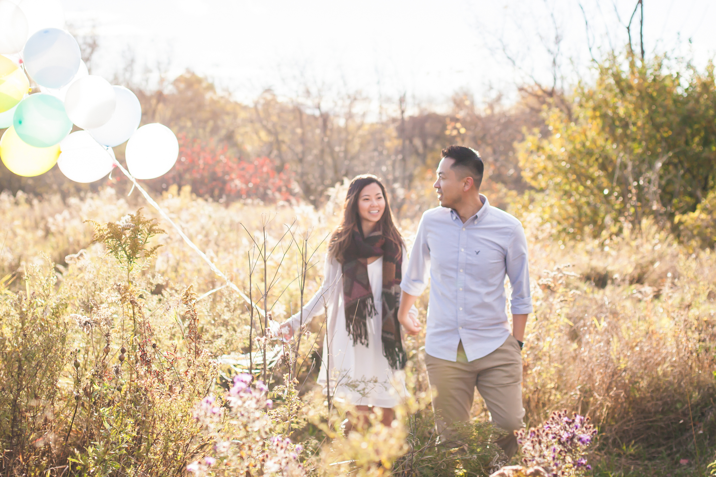 Outdoor engagement session on a field with pastel balloons