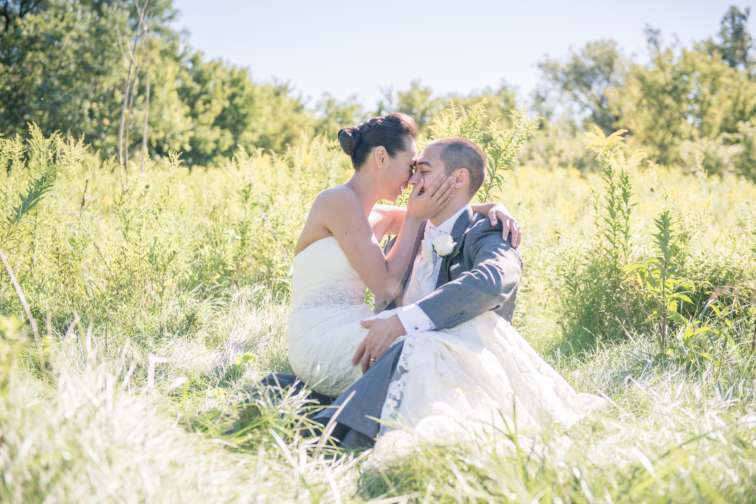 Bride and groom sitting in the middle of a sun lit field