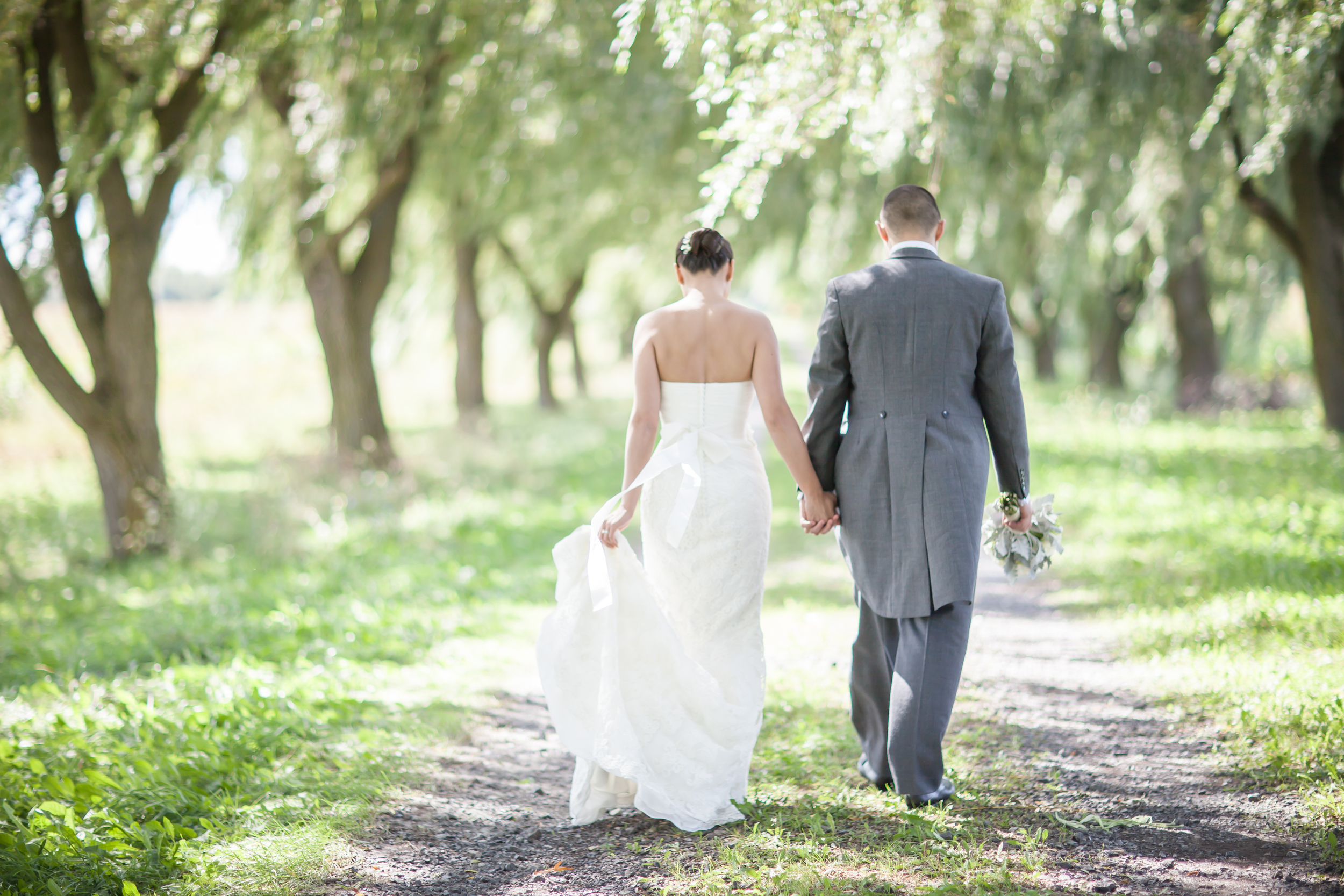 Bride and groom walking through a willow tree farm