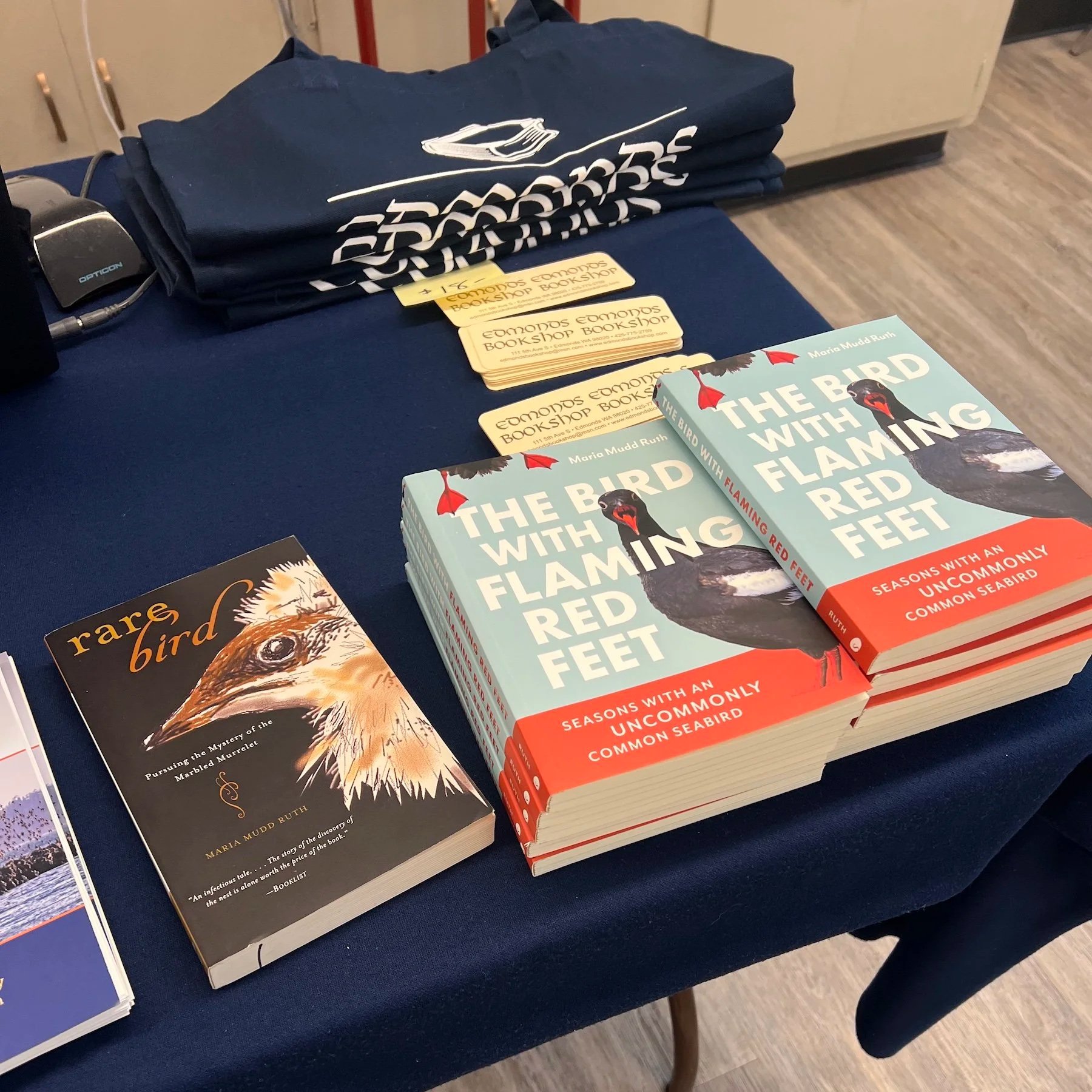 Picture of a table with blue tablecloth and a stack of books. One book is titled Rare Birds and the other book is titled The bird with the flaming red feet.
