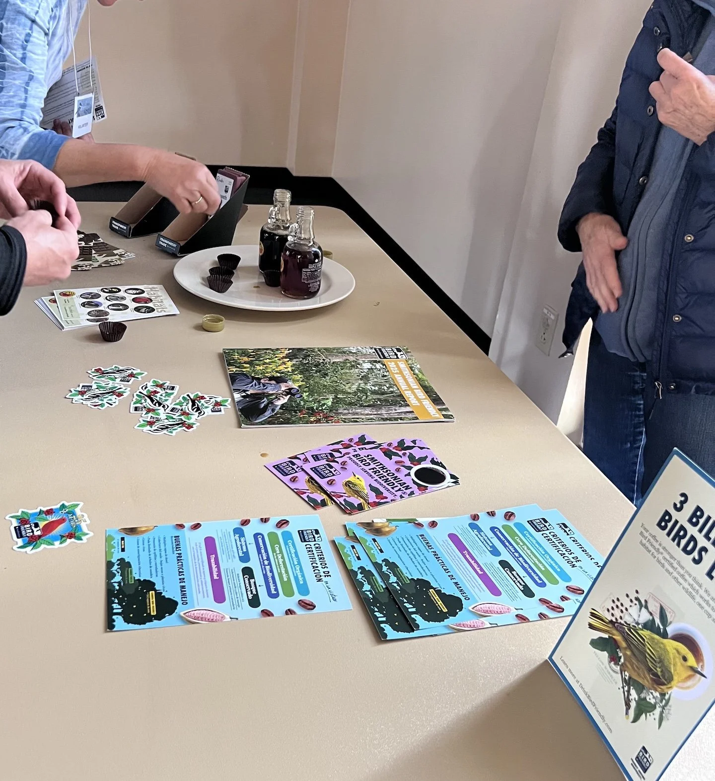 Table with stickers, food samples and flyers about Bird Friendly chocolate and maple syrup.