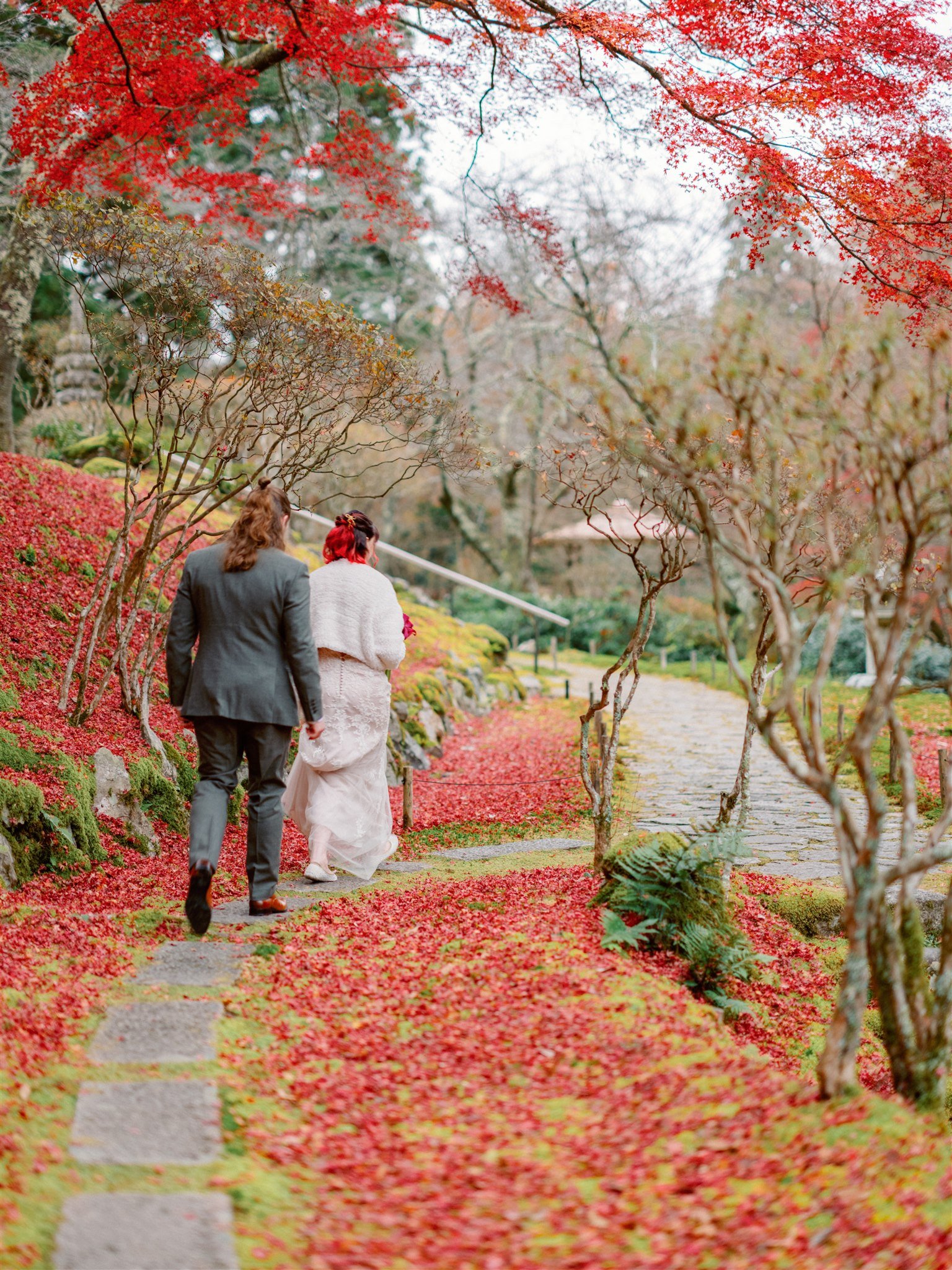 Couple stroll through vibrant red autumn foliage during their Japanese garden elopement. 