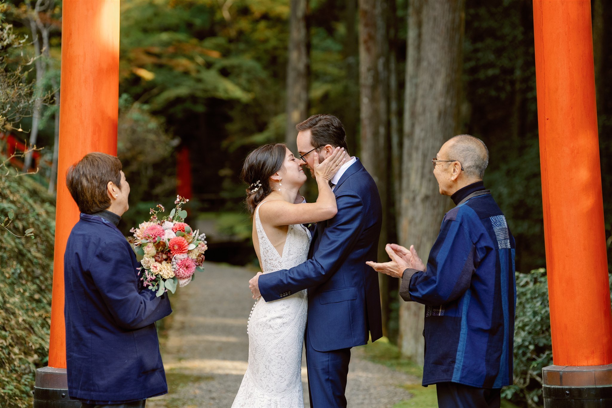 Couple share a kiss at their wedding elopement ceremony under a Torii gate. 