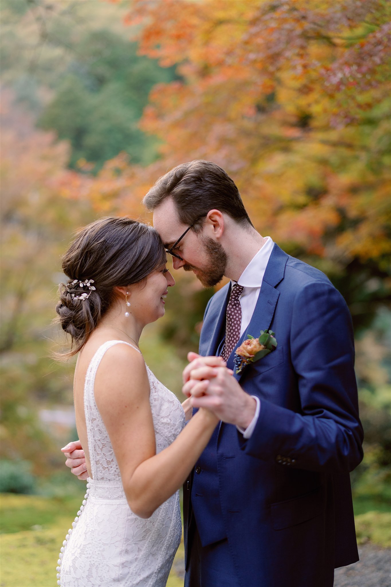 Couple dance during their elopement with autumn foliage in the background. 