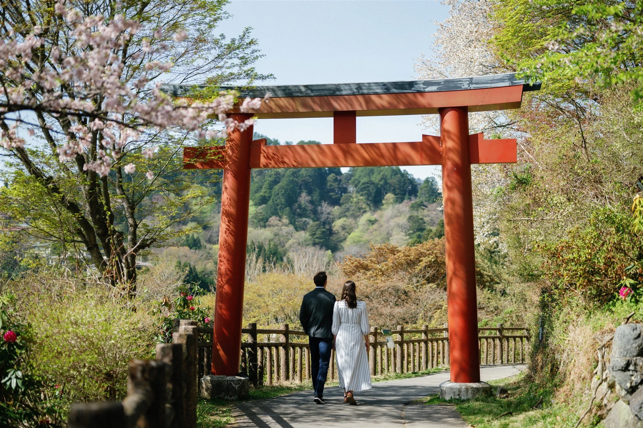 Adventure elopement couple walking underneath Japanese Torii gate. 