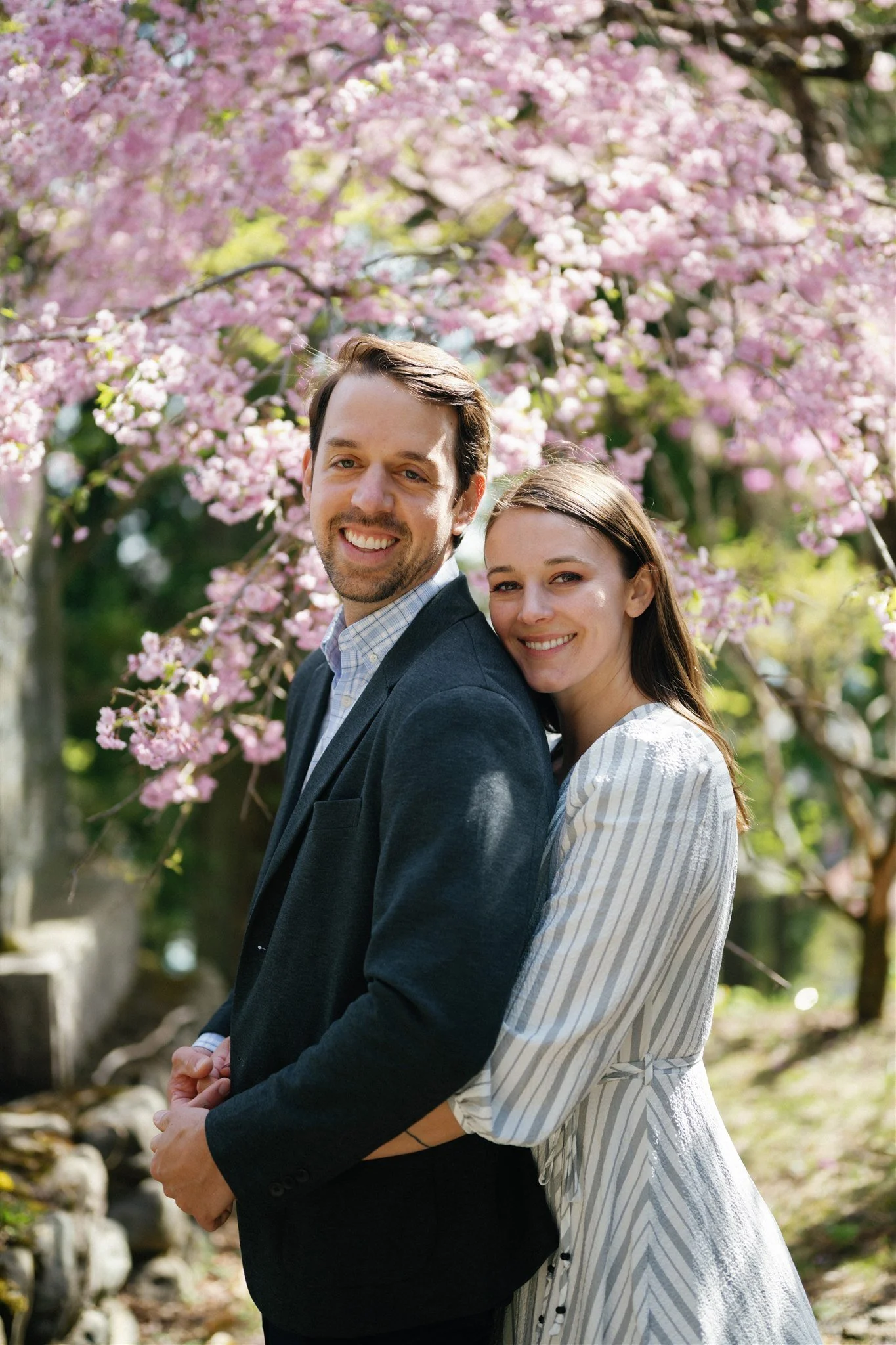 Japan elopement couple pose under cherry blossom tree. 