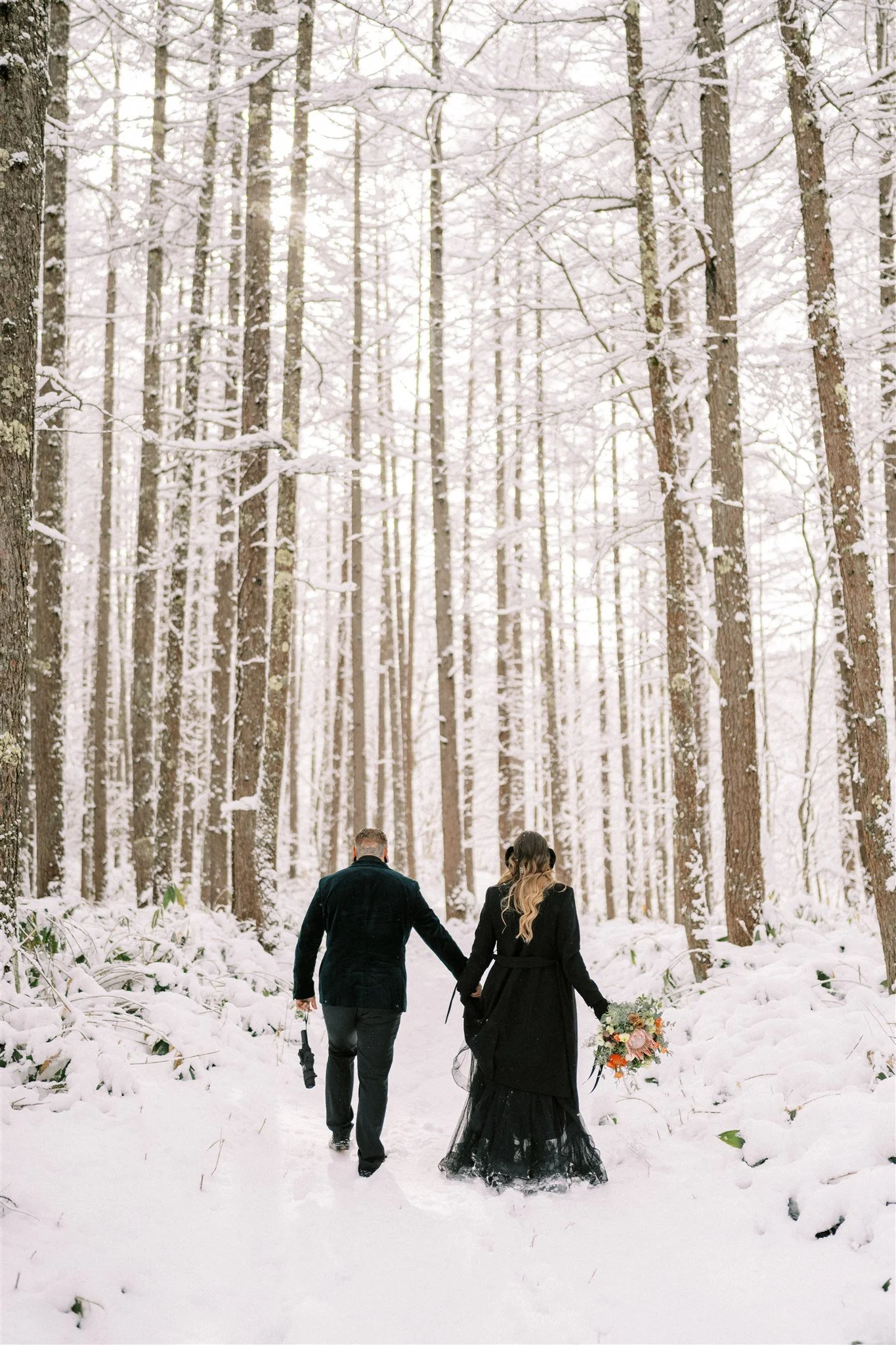 Winter elopement couple standing in snow covered trees