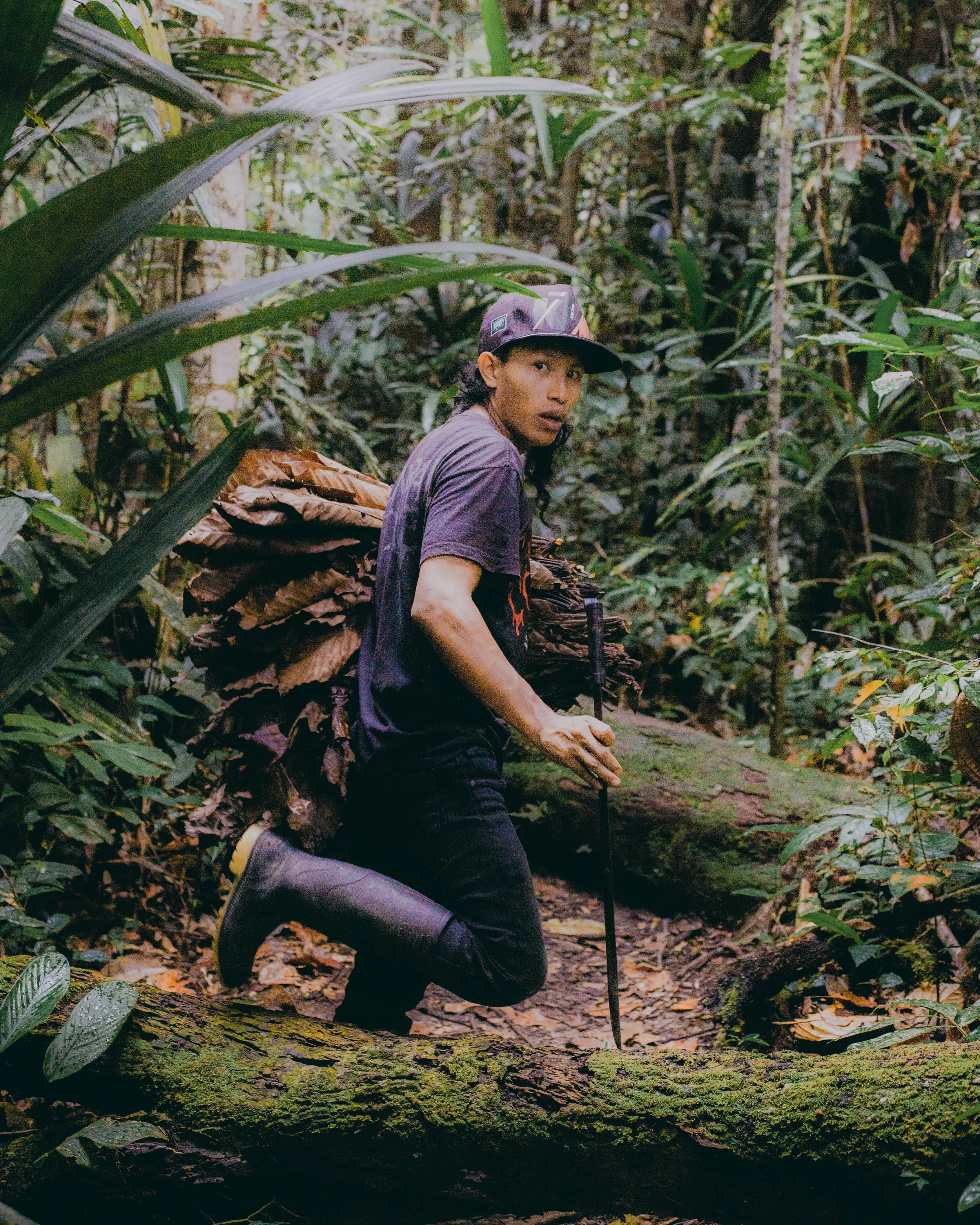 pilots his boat, leading tourists on a four-day expedition into the Peruvian side of the Amazon forest. Accompanying him is his son, Rober, captured in the foreground of the image, peacefully asleep. At 11 years old, Rober follows in his father's foo