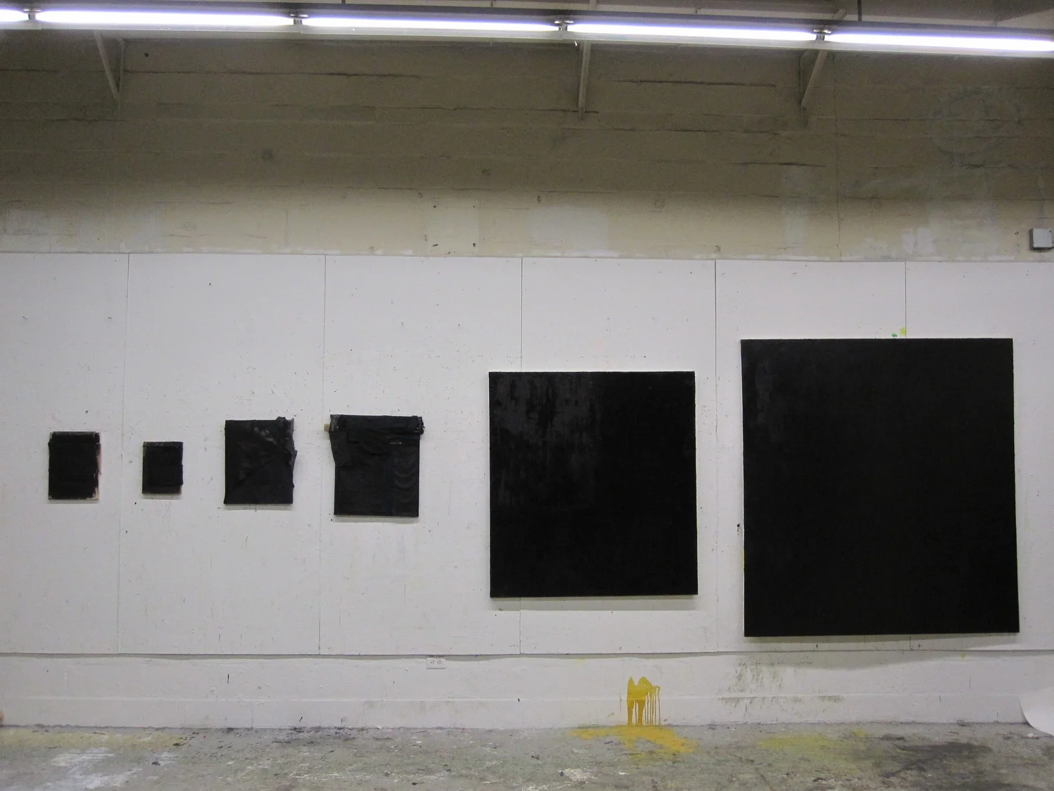An installation shot of six predominantly black paintings taken at Rhode Island School of Design in 2011