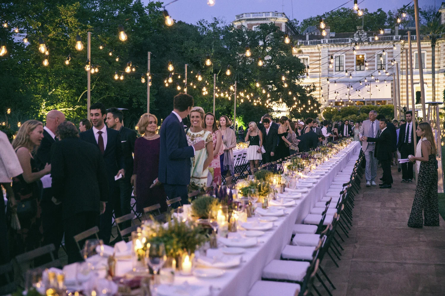 VAN WYCK Bistro lights at an outdoor reception dinner hang overthead at a Tuscan wedding. #WeddingDecor #DestinationWedding