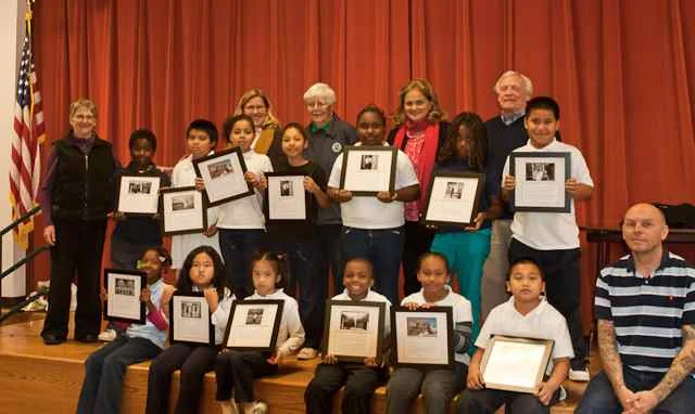 Bayside School third graders proudly display photos from their field trip, after receiving congratulations from teacher Paula Hammons(l.) and Historical Society members including Schools Program co-chairs Susan Frank (second from right, top row), and Bob Woodrum (bottom right).