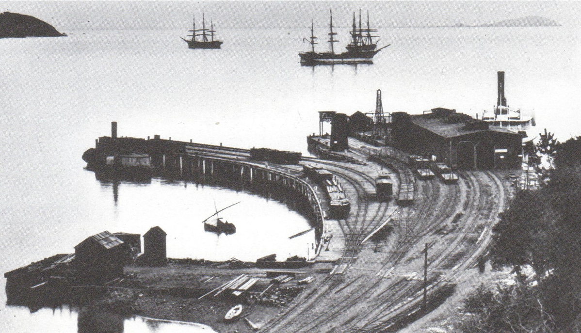 Sausalito rail and ferry wharf, with its narrow-gauge track, about 1890. The ferry San Rafael is in the slip at right, and three square riggers ride at anchor offshore.