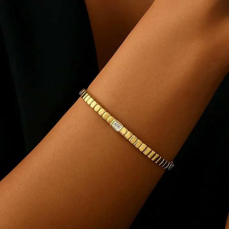 Model wearing a 14K yellow gold emerald cut diamond bangle with a sleek, minimalist silhouette.