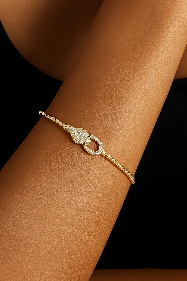 Model wearing a 14K yellow gold diamond and emerald snake bangle with pavé-set diamonds.