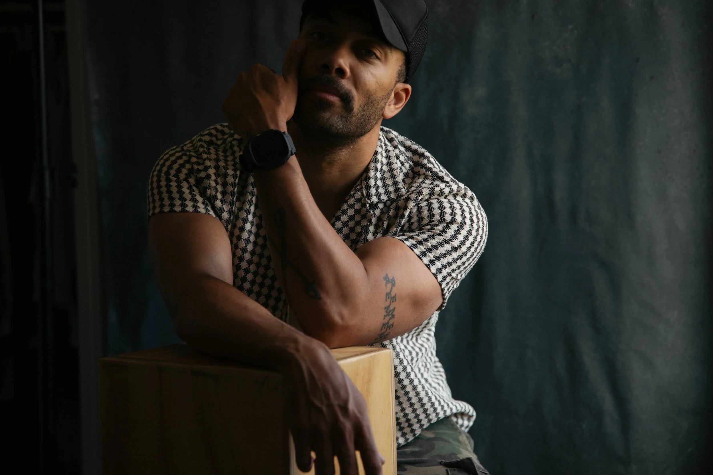 Portrait of photographer Cameron story shot with natural light from the right of the frame against a dark navy blue background