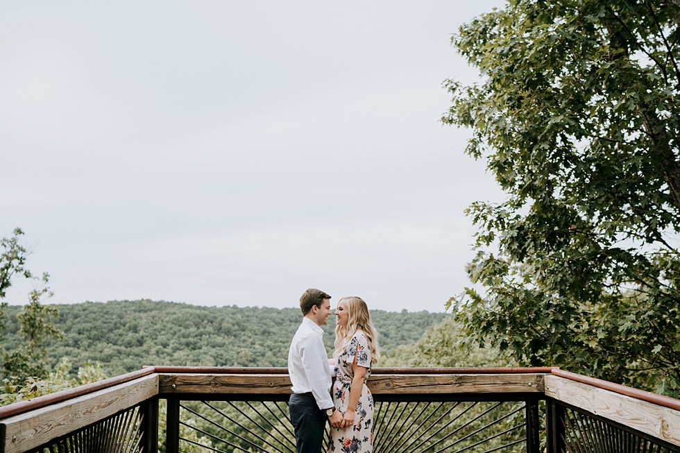  Overlook photo of engaged couple in embrace soon to be bride in floral dress at Bernheim Forest #engagementphotographer #bernheimforest #engagementgoals #kentuckyengagementphotographer #kentuckyphotographer #engagementsession #photographyanddesignby