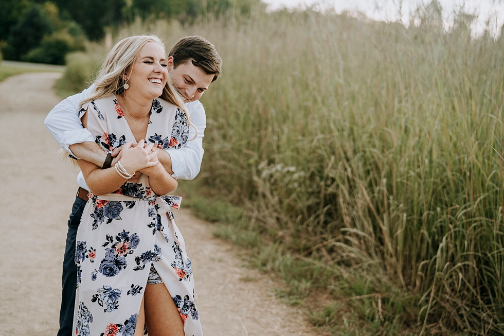  Groom to be hugs bride to be from behind as they walk down forest path together #engagementphotographer #bernheimforest #engagementgoals #kentuckyengagementphotographer #kentuckyphotographer #engagementsession #photographyanddesignbylauren 