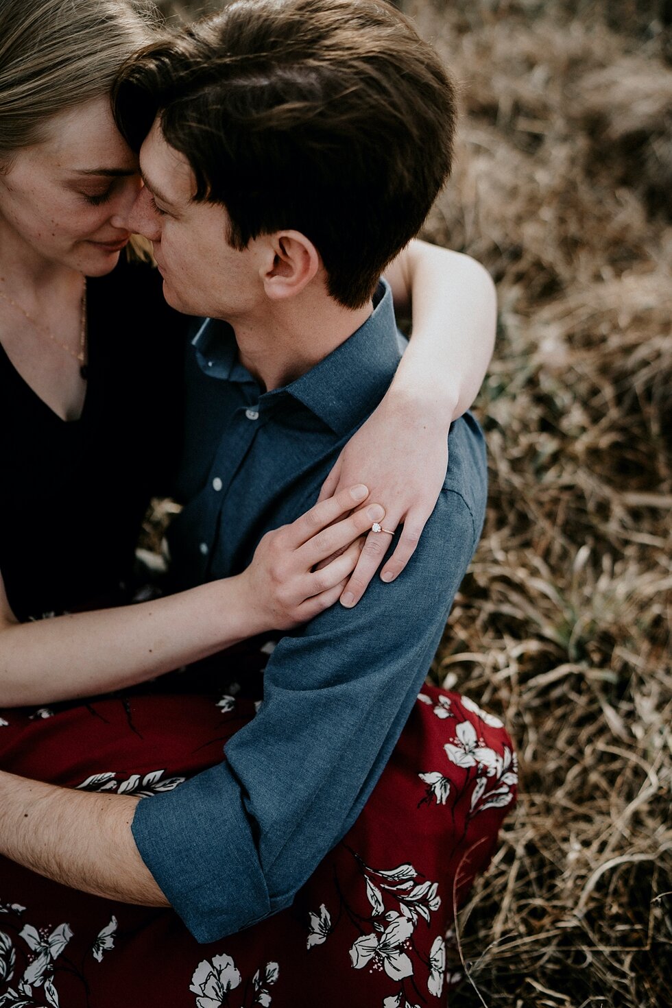  Absolutely stunning engagement ring with a gold band displayed perfectly as this couple held each other close. Kentucky mountains red floral skirt dark black shirt cloudy skies engagement session Photography by Lauren outdoor #photographybylauren #k