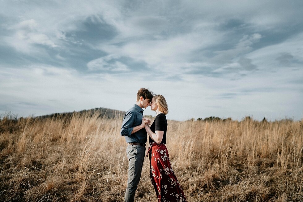  Hand in hand this soon to be bride and groom were elated as they celebrated their engagement to be married. Kentucky mountains red floral skirt dark black shirt cloudy skies engagement session Photography by Lauren outdoor #photographybylauren #kent