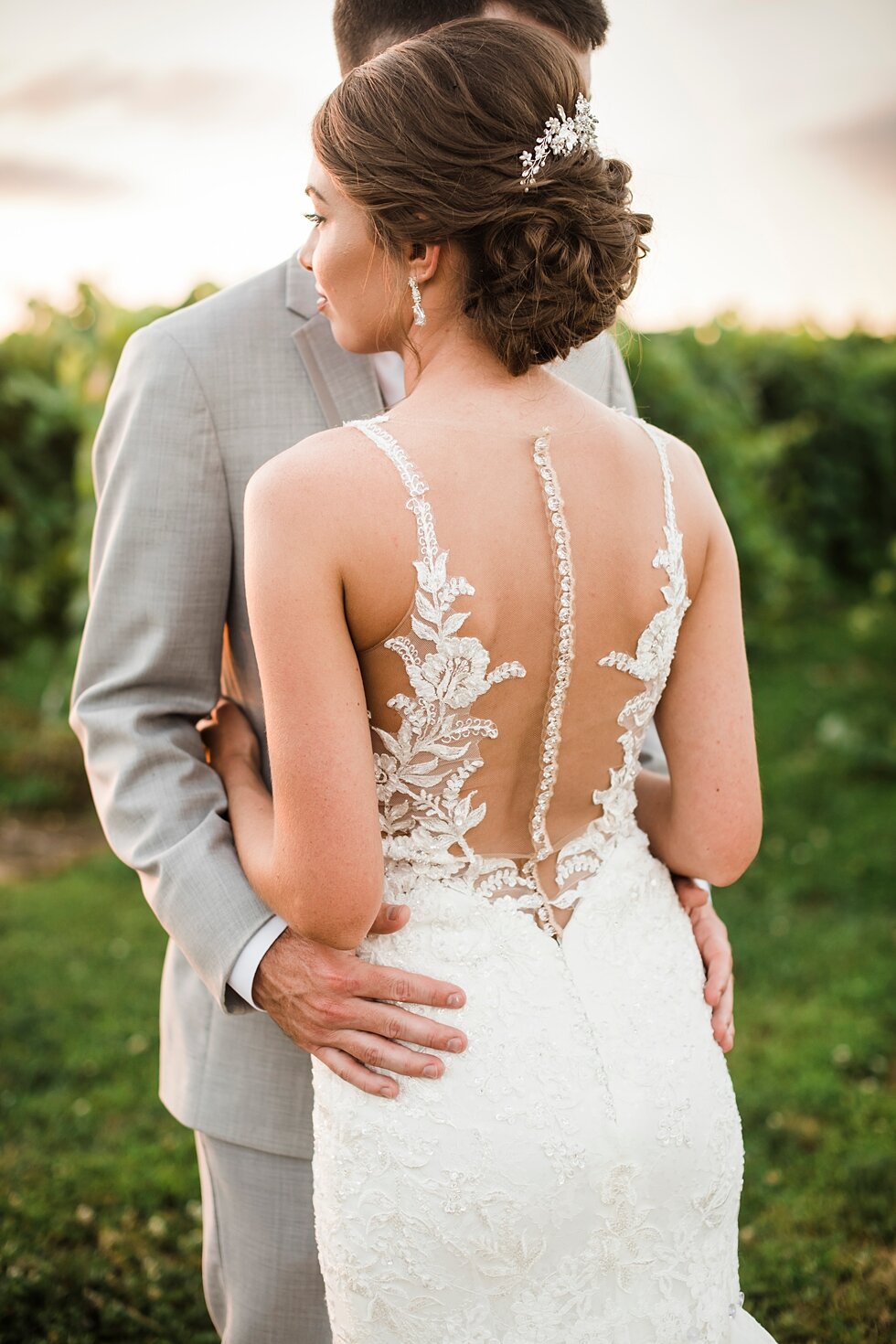 The bride shows off her lace and sheer wedding dress back as she holds her new husband outside as the sun sets. wedding ceremony details stunning photography married midwest louisville kentucky #weddingphoto #love #justmarried #midwestphotographer #