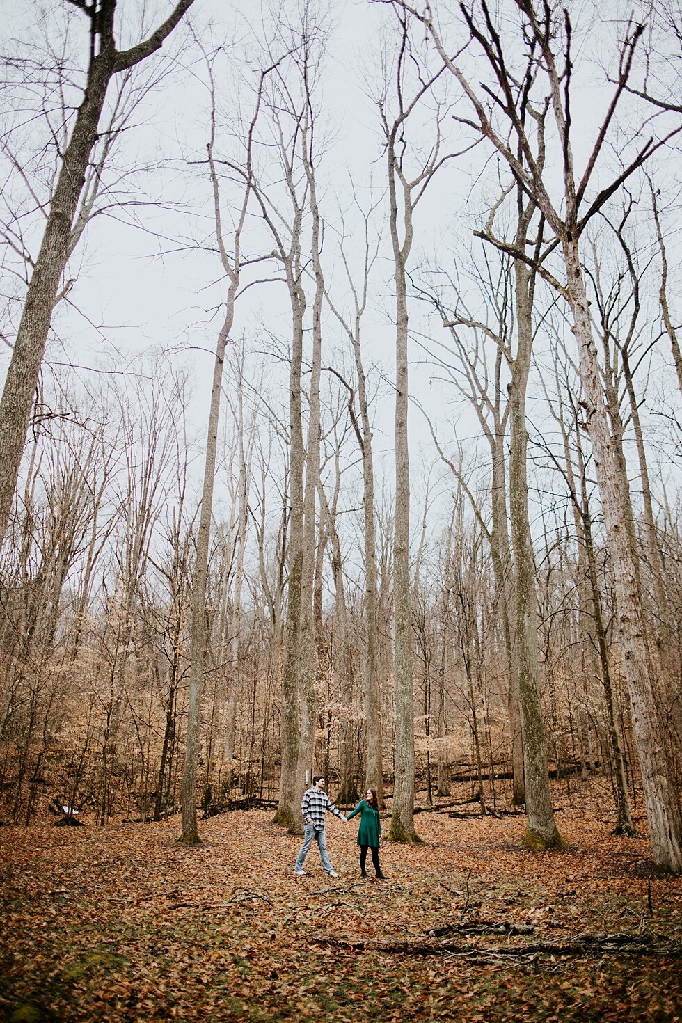  This engaged couple wore a great combination of colors and patters that stood out against the rainy winter backdrop that Bernheim Forest provided. Louisville photographer winter engagement Bernheim Forest emerald green dress plaid shirt rainy day Ke