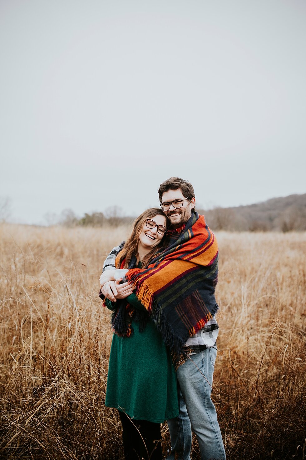  Nothing but smiles from this bride and groom to be during their engagement session as the snuggle under a blanket on a rainy winter day in Louisville, Kentucky. Louisville photographer winter engagement Bernheim Forest emerald green dress plaid shir