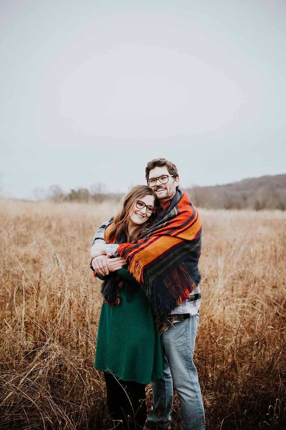  Engagement goals for this couple as they huddle under a stunning bright orange and red blanket on this rainy winter day in Kentucky. Louisville photographer winter engagement Bernheim Forest emerald green dress plaid shirt rainy day Kentucky couple 