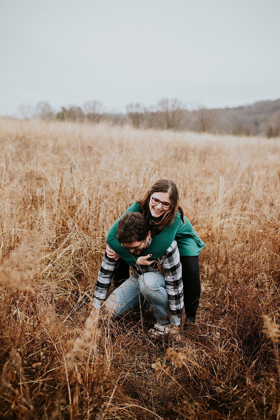  Piggy back ride for this sweet couple during their engagement session. Louisville photographer winter engagement Bernheim Forest emerald green dress plaid shirt rainy day Kentucky couple outdoor engagement  #savethedates #engagementphotography   #ga