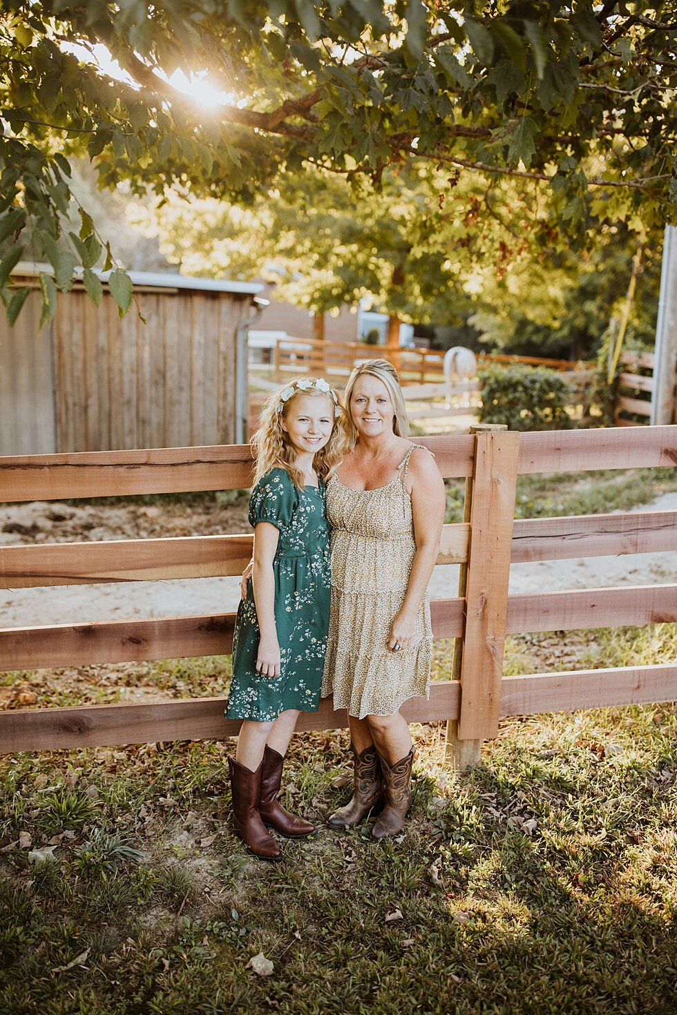  Mother and daughter duo posing against the rustic farm fence in beautiful dresses during their fall photo session in Louisville, Kentucky. Fall Louisville Kentucky photographer mother daughter photography session portraits loving relationship wester